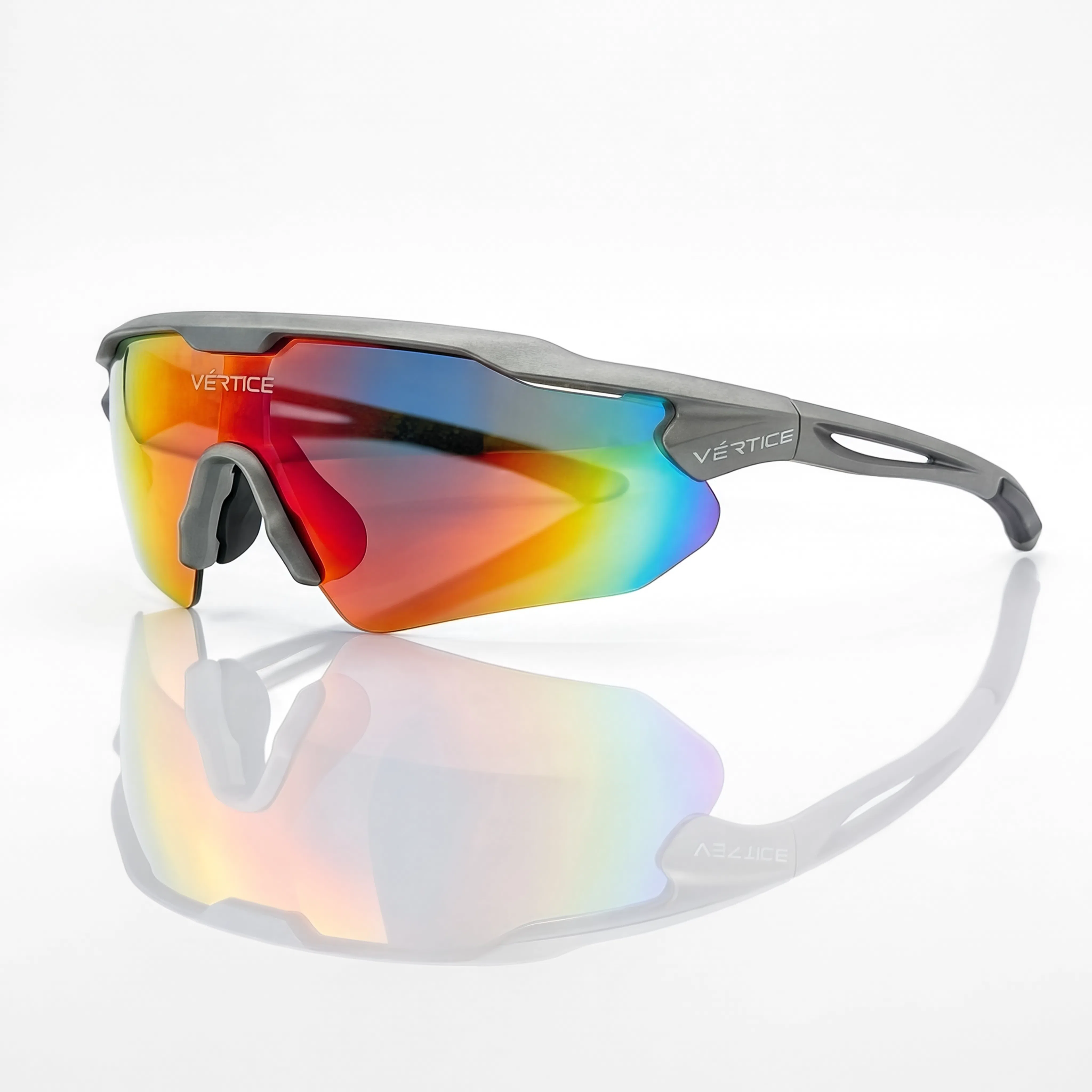 Vetice sport sunglasses with a matte gray frame and a vibrant iridescent shield lens showing red, orange, yellow, and blue reflections, displayed on a reflective white surface.